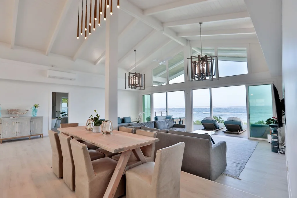 Una sala de estar y comedor de planta abierta tiene grandes ventanas con vistas al agua.