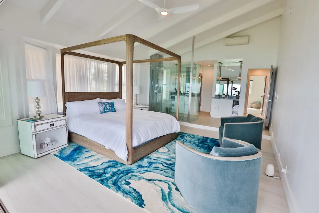 Un dormitorio luminoso con una cama con dosel y una alfombra azul estampada.