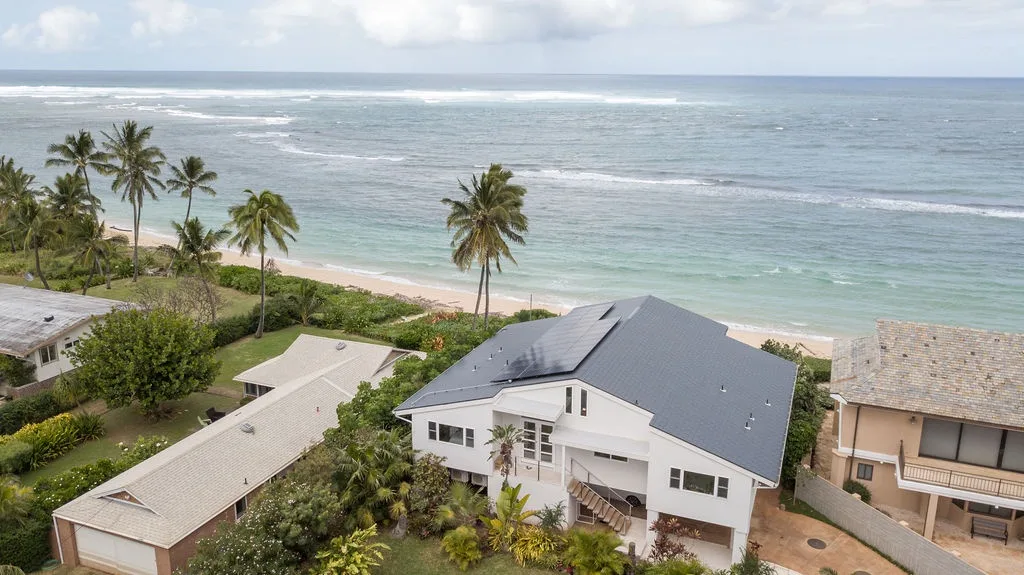 Vista aérea de una casa costera junto a una playa y el océano.