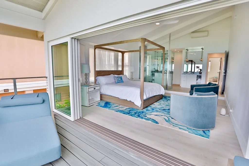 Un dormitorio con cama con dosel y asientos azules junto a puertas corredizas de vidrio.