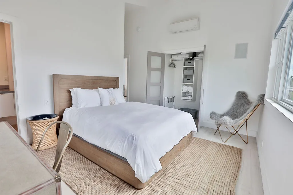 Un dormitorio luminoso con una cama bien tendida y una alfombra tejida.