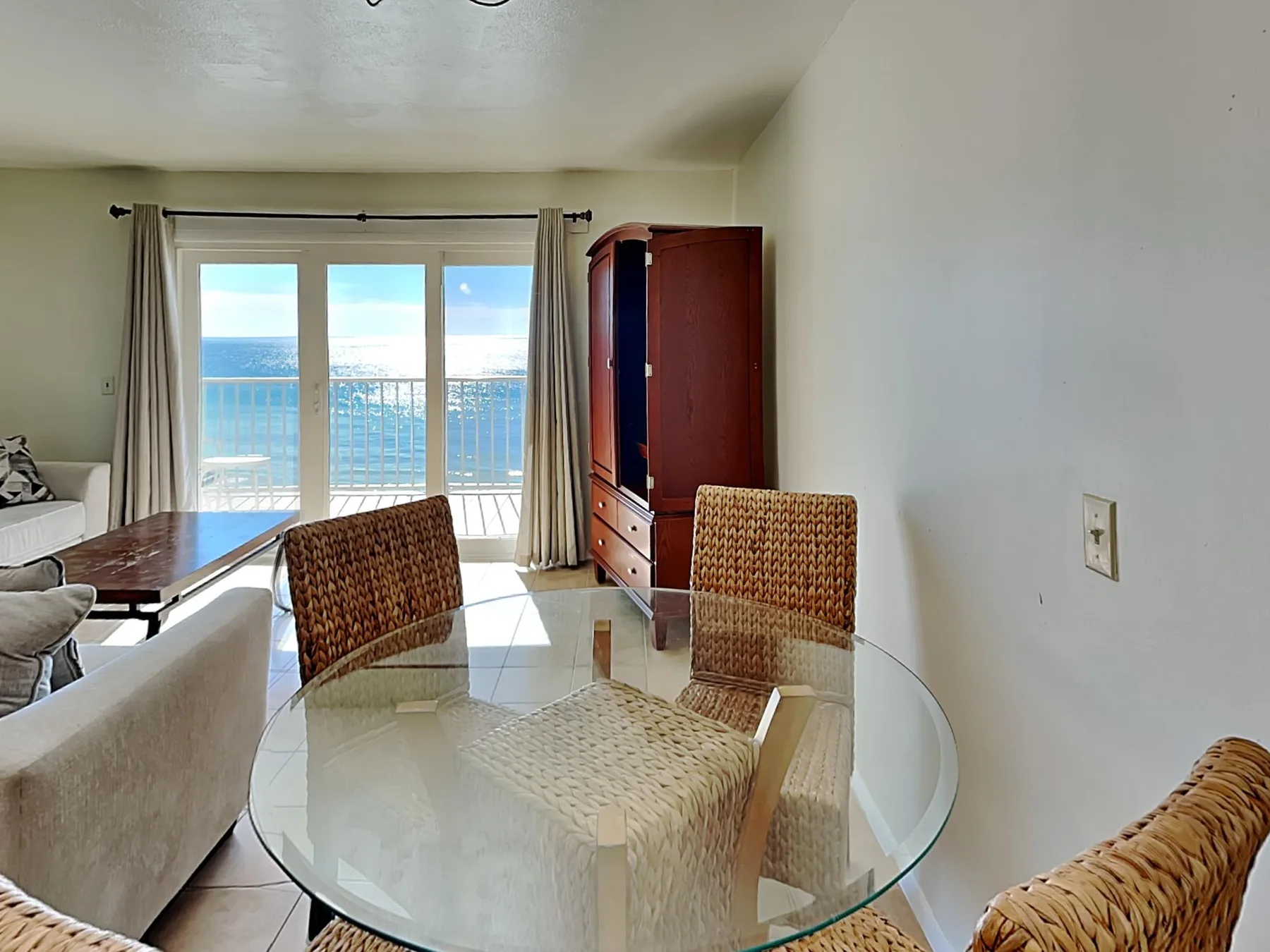 A dining area with glass doors opening onto a balcony overlooking the water.