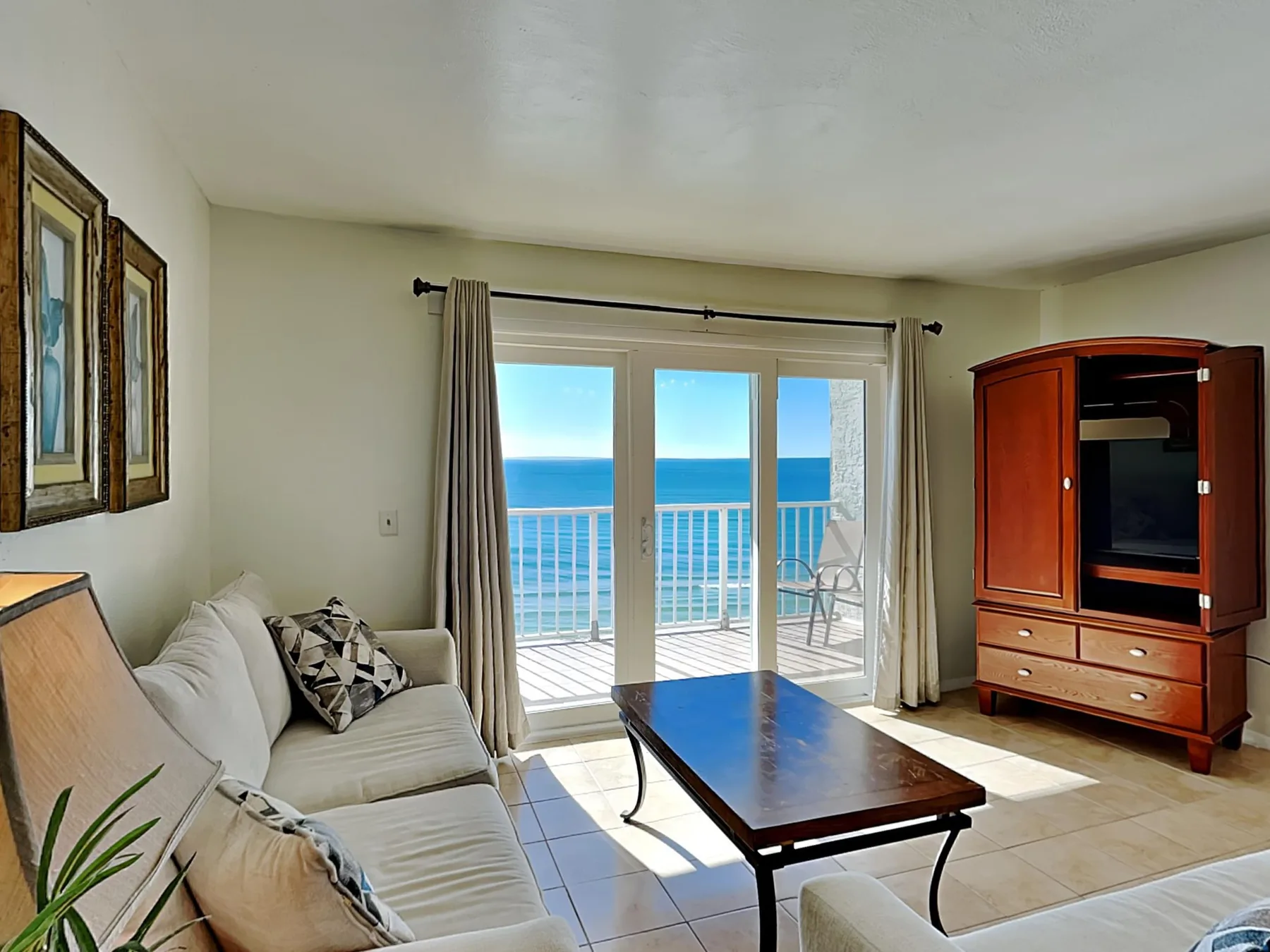 A bright living room has seating, a coffee table, and glass doors opening onto a balcony.