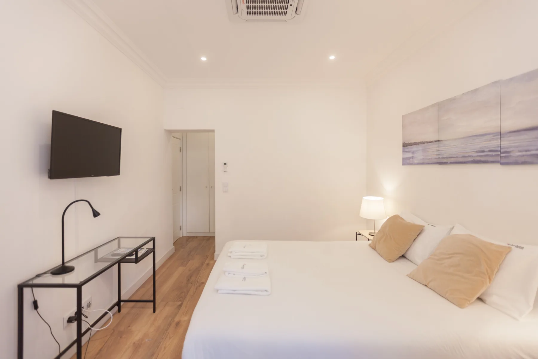 A bright bedroom with a large bed and a wall-mounted television.