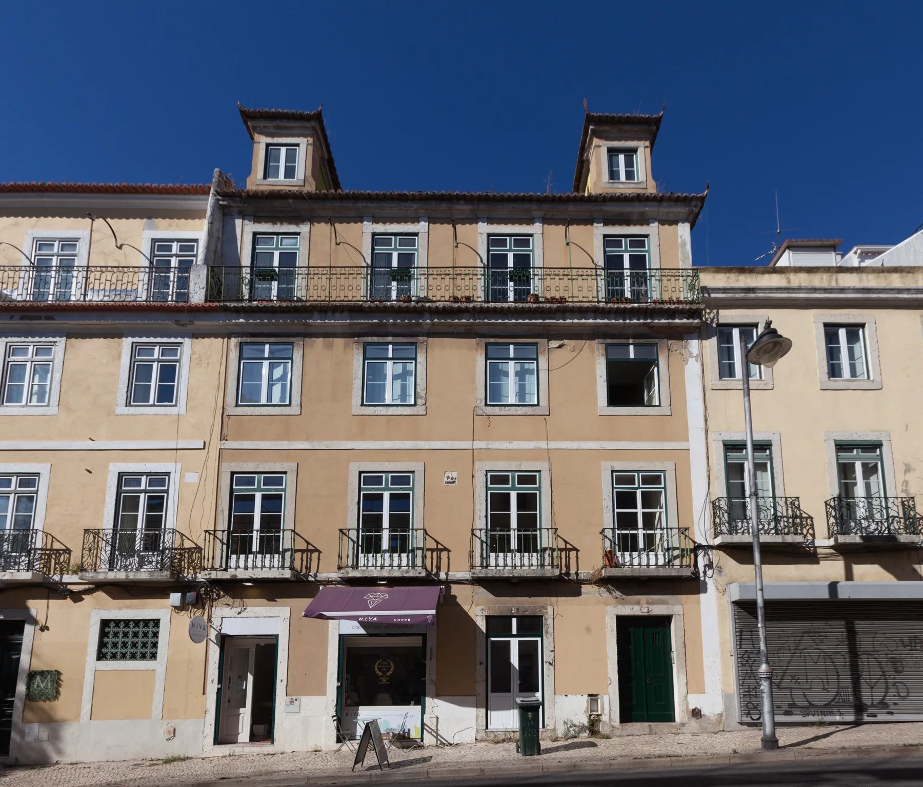 A row of historic-looking city buildings with balconies beneath a clear blue sky.