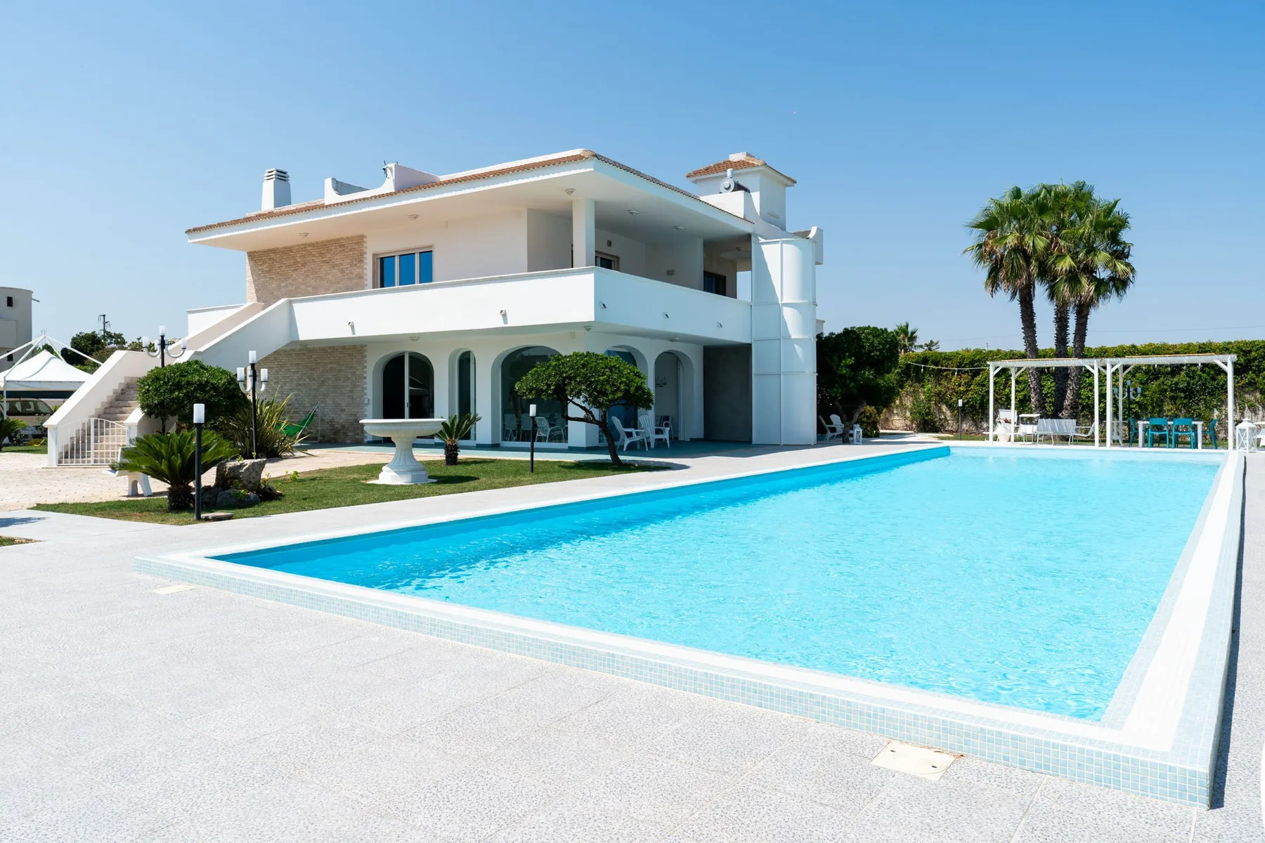 A modern house stands beside a large outdoor swimming pool.