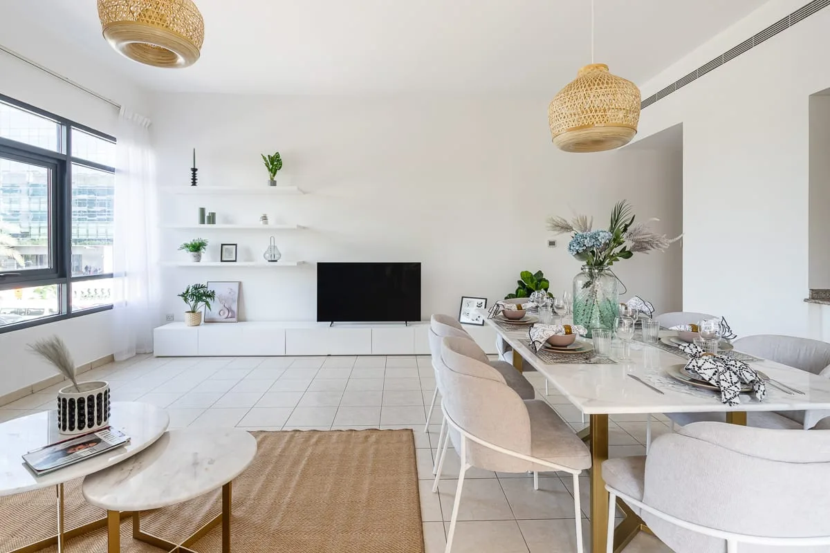 Luminoso espacio abierto de sala y comedor con un televisor y una mesa larga.