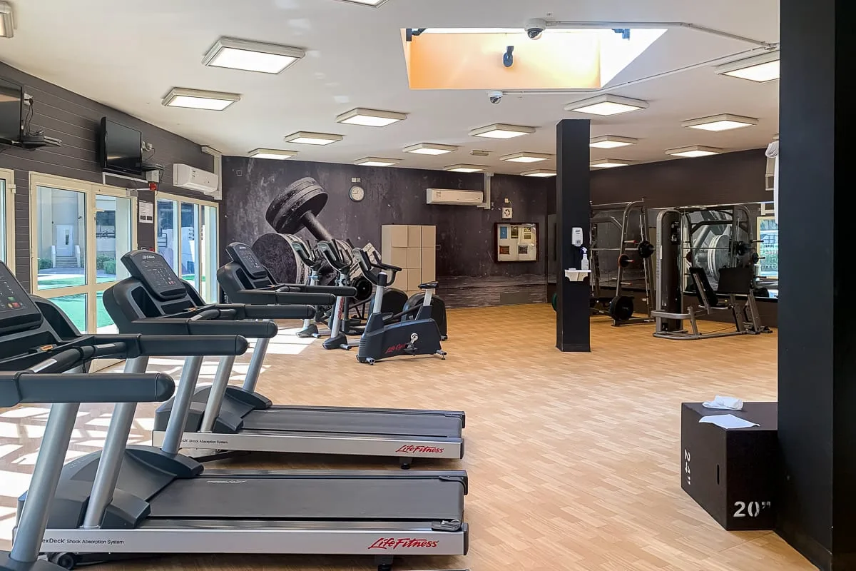 Un gimnasio con cintas de correr, bicicletas estáticas y máquinas de pesas.