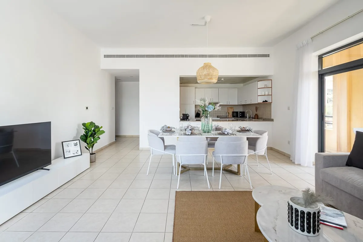 Una luminosa sala-comedor de planta abierta con cocina y ventanales.