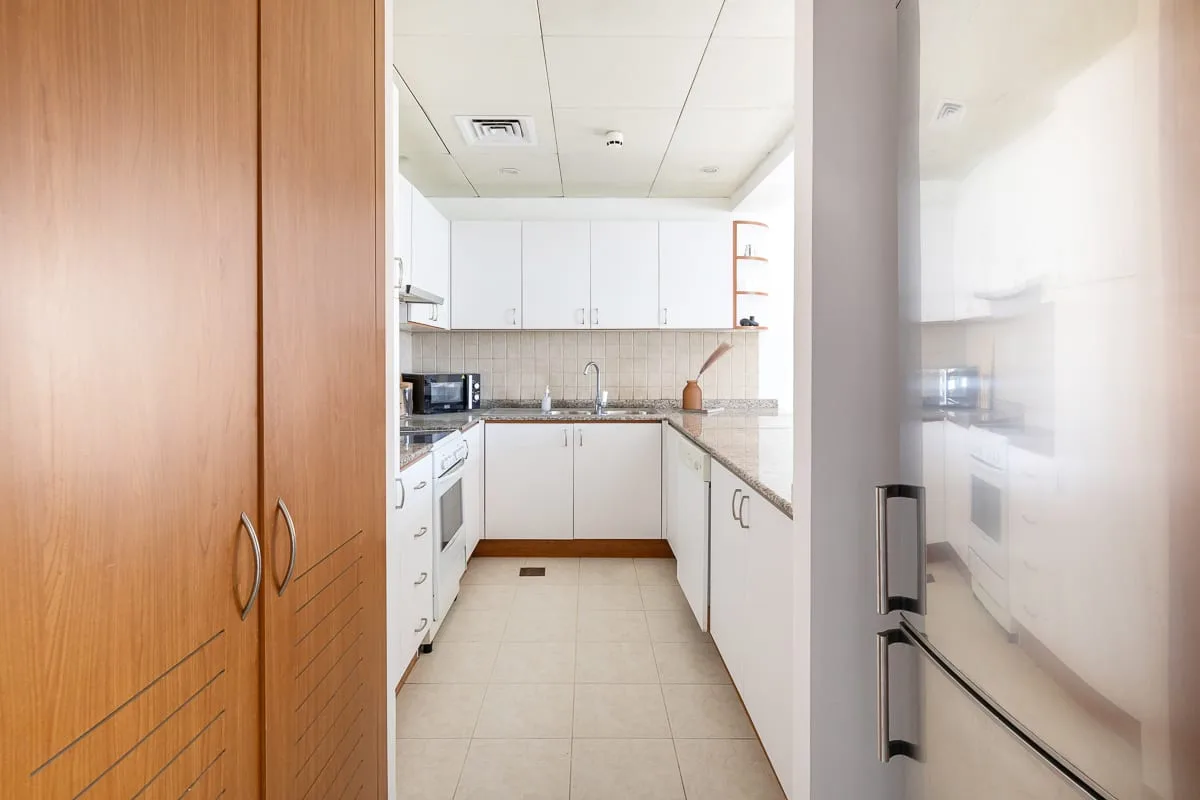 Una cocina compacta con gabinetes blancos, encimeras y electrodomésticos integrados.