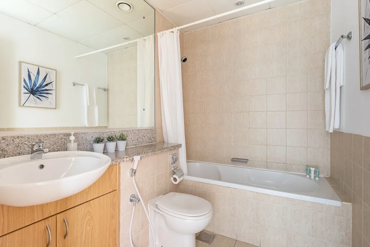 Un baño con lavabo, inodoro y bañera detrás de una cortina de ducha.
