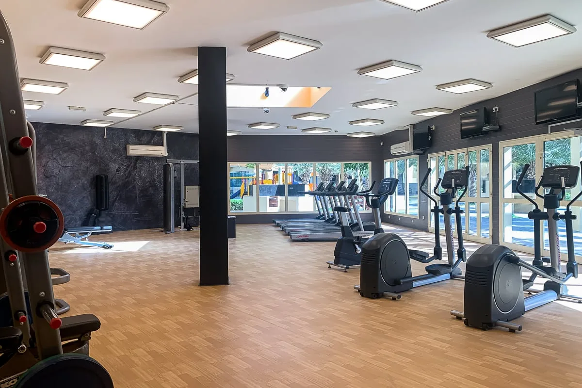 Un gimnasio amplio con máquinas de ejercicio y grandes ventanales.