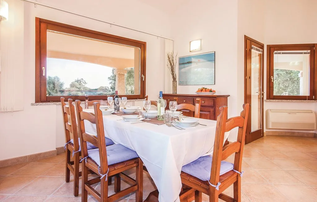 A dining room with a set table and wooden seating beside a large window.