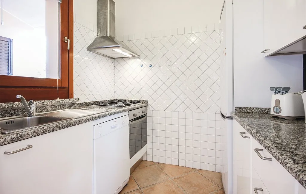 A bright kitchen with white cabinets, tiled walls, and a countertop.