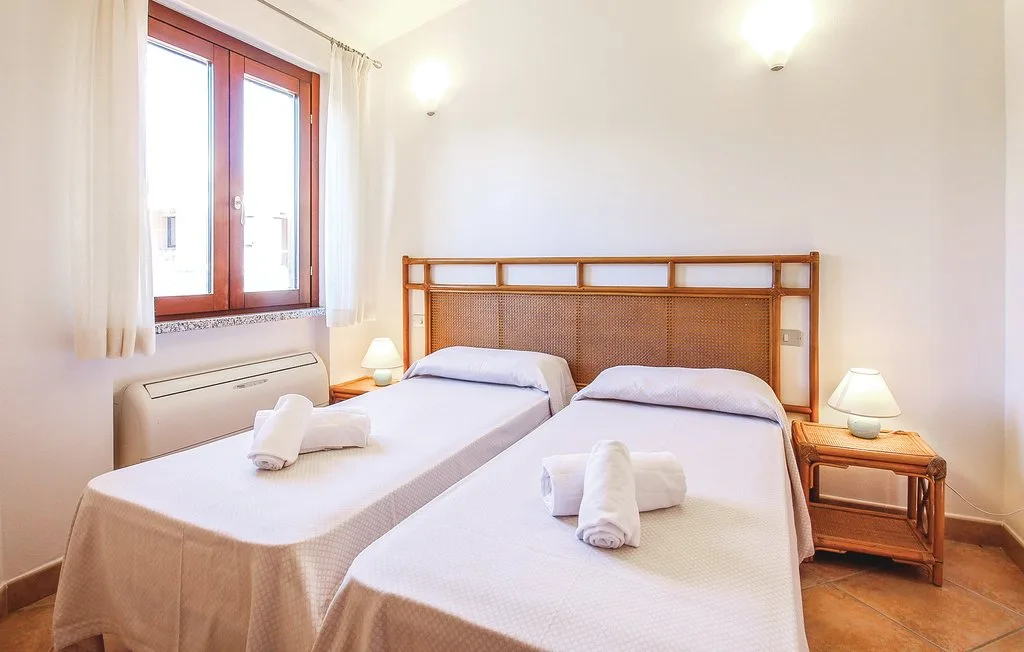A twin bedroom with two beds beside a tall window.