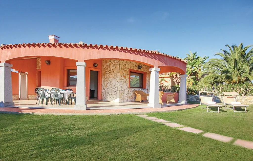 A terracotta-colored house opens onto a covered patio beside a green lawn.