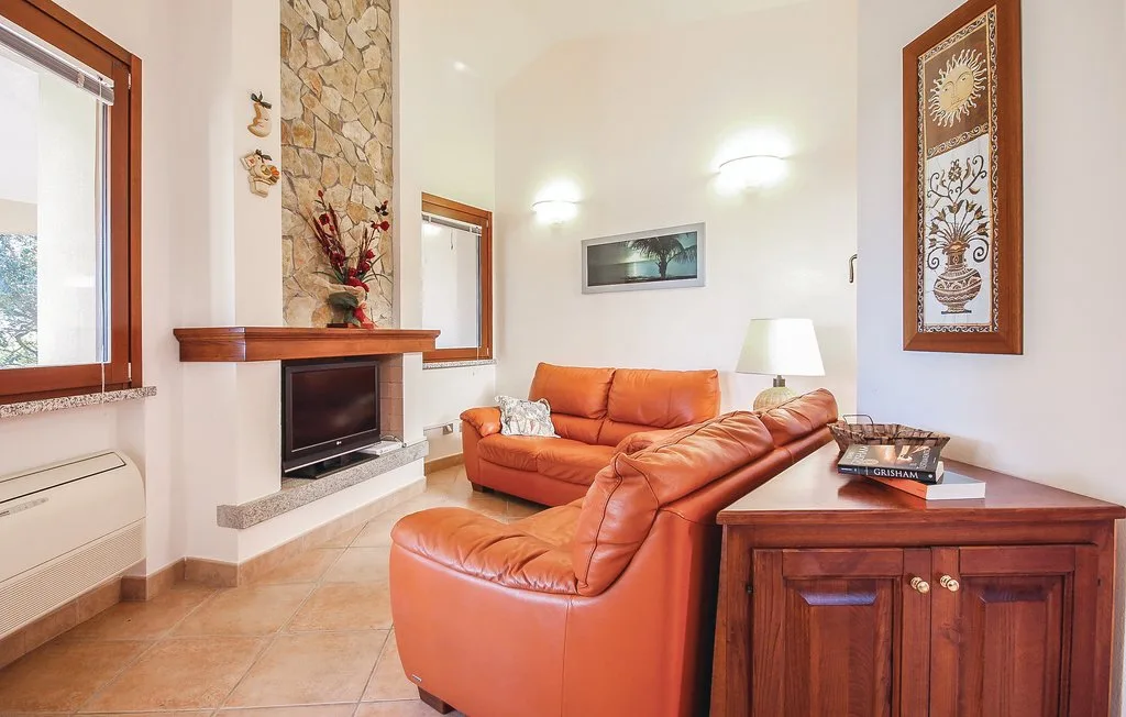 A living room with orange seating, a television, and a wooden sideboard.