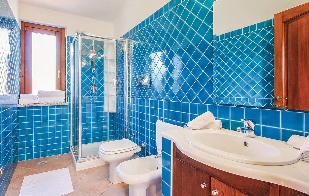 A tiled bathroom with a glass shower and a bathtub beside the sink.