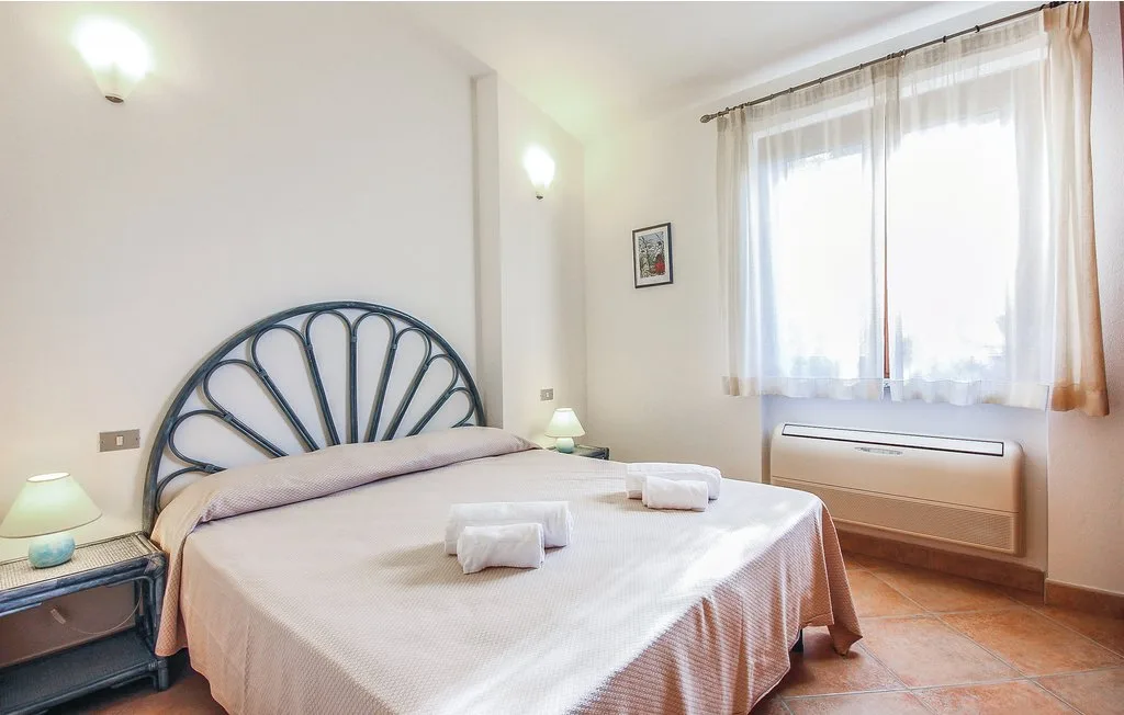 A bedroom with a double bed beneath a bright window.