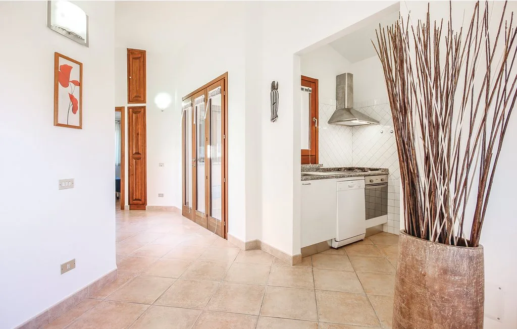 A bright tiled hallway opens onto a kitchen with a countertop and range hood.