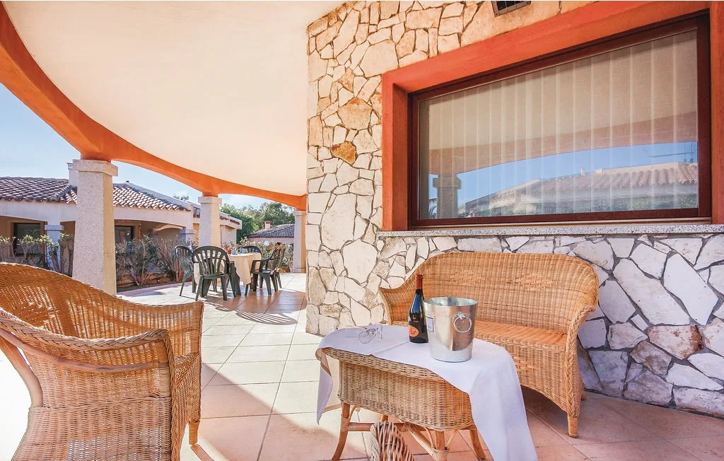 A covered patio with woven seating and a stone wall.