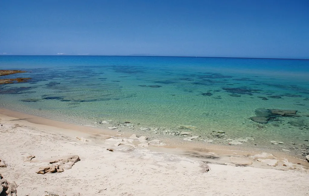 A sandy beach slopes toward clear turquoise water.