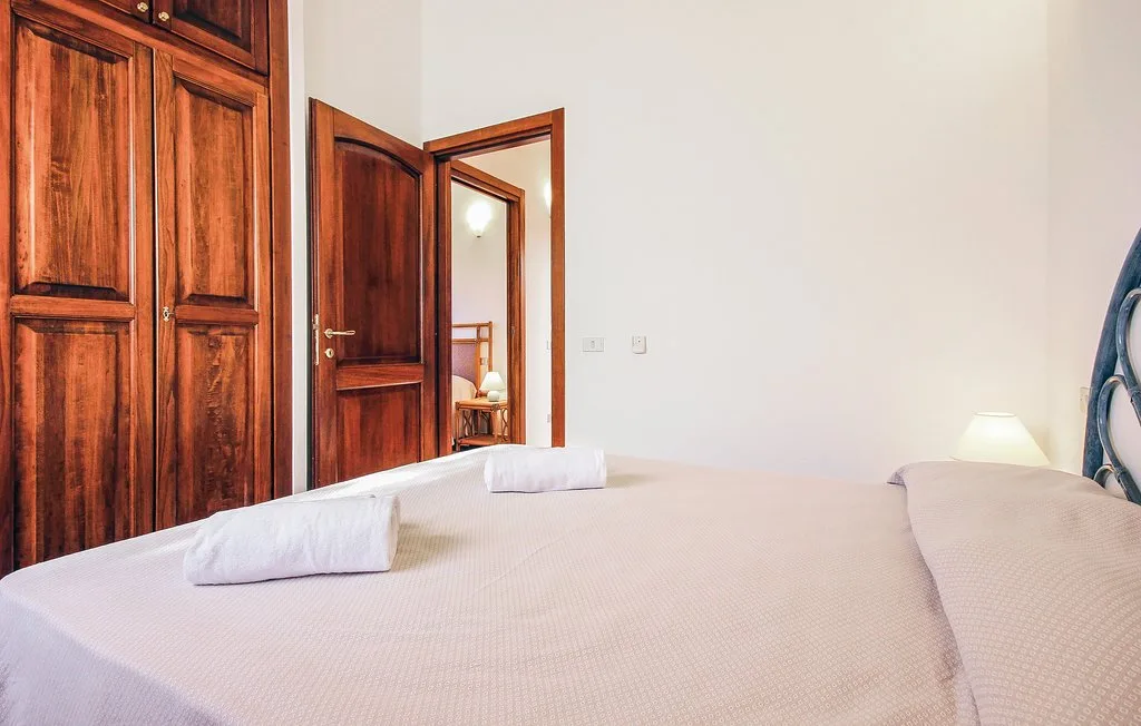 A bedroom with a bed, folded towels, and wooden doors.