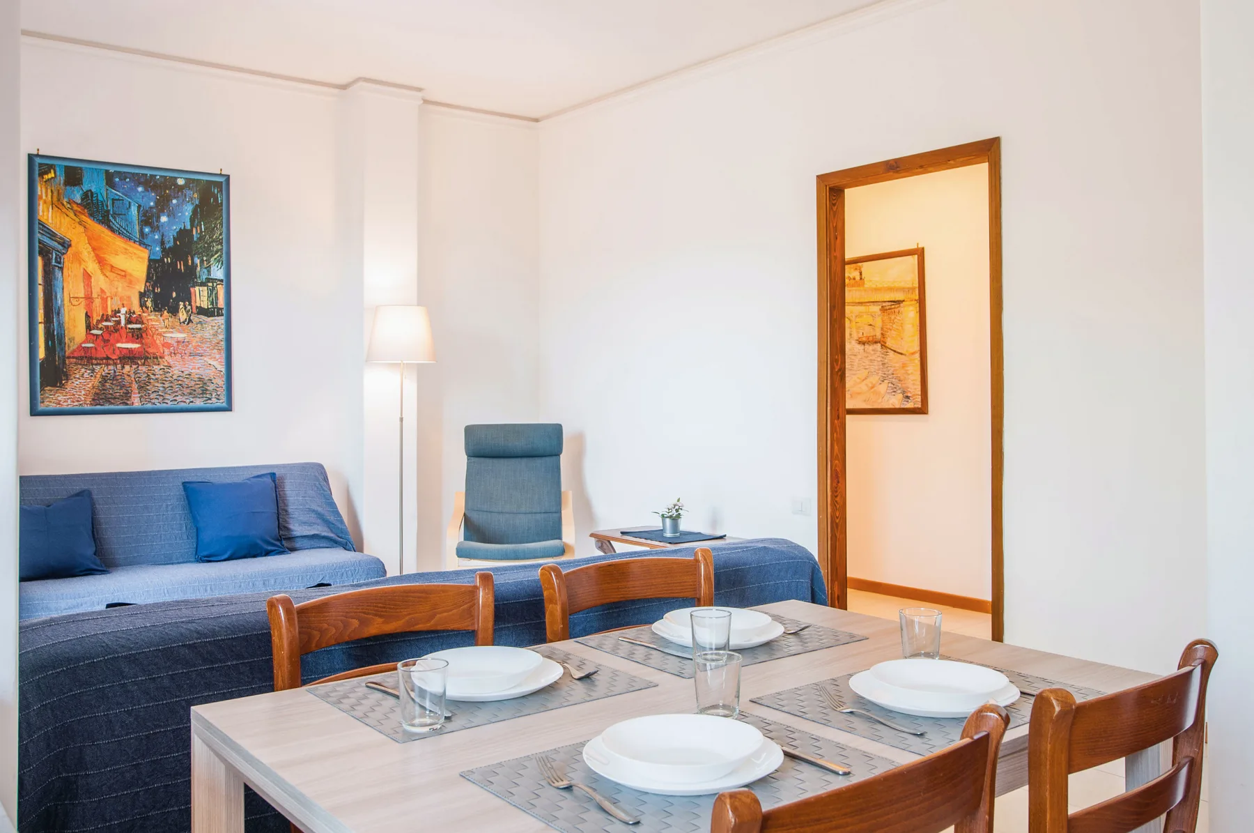 A bedroom and dining area with a set table beside the bed.