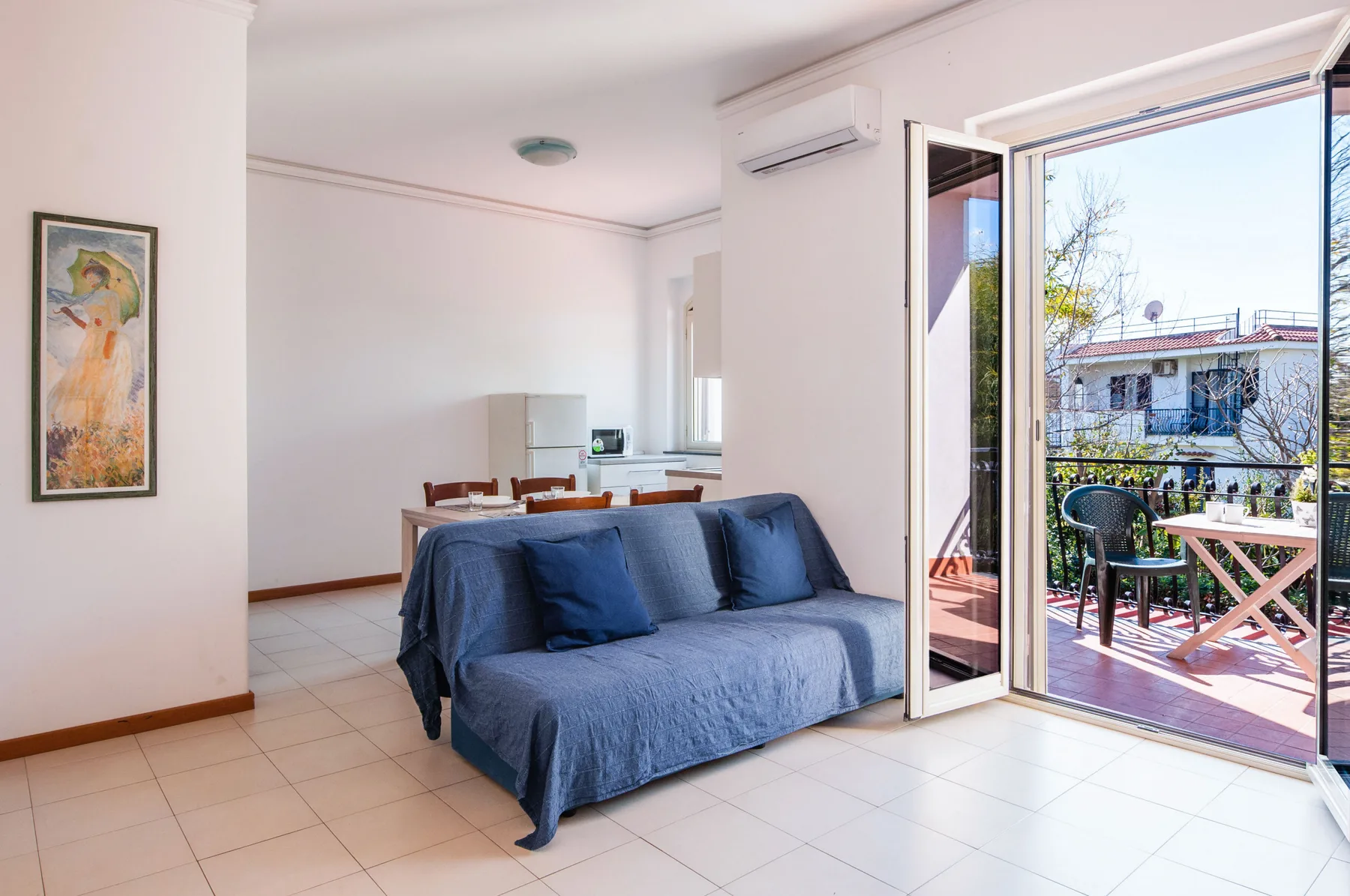 A bright living room with blue seating and open doors to a balcony.