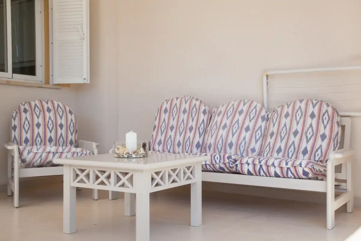 Una zona de estar amueblada con cojines estampados y una mesa de centro blanca.