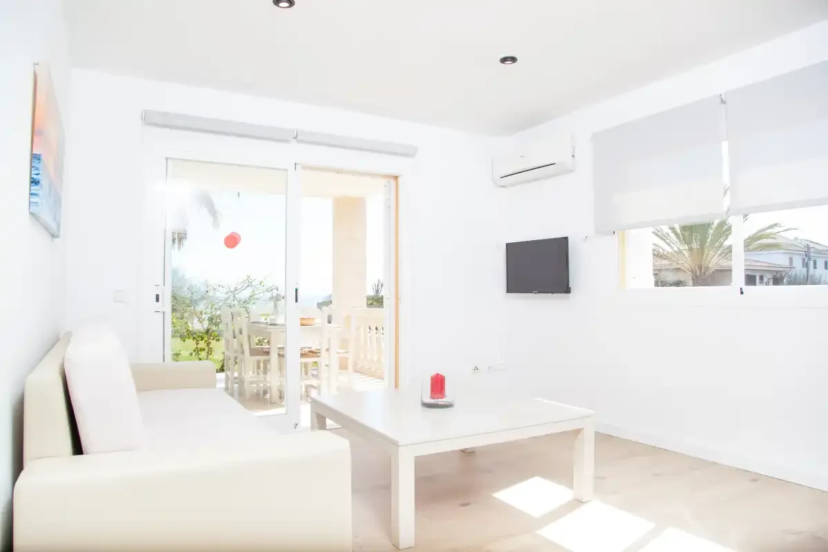 Un salón luminoso con asientos, una mesa de centro y puertas acristaladas que dan a un balcón.