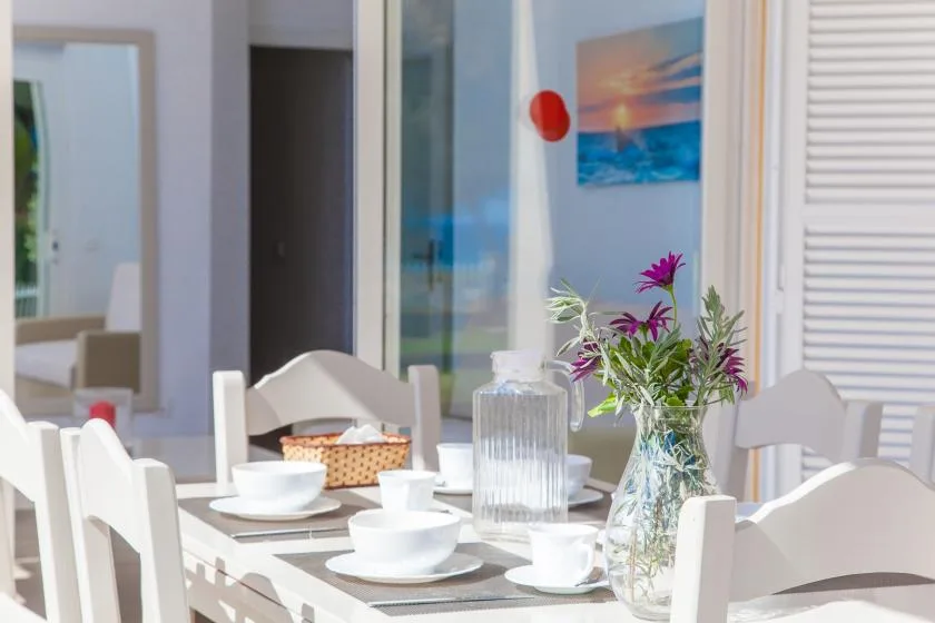Un comedor luminoso con una mesa puesta y un jarrón de flores.