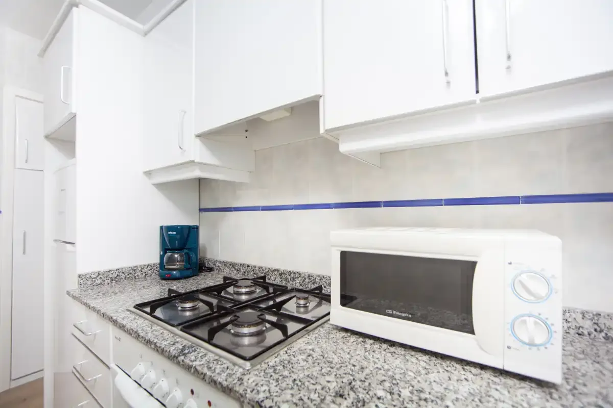 Una cocina luminosa con una placa de gas y un microondas sobre la encimera.
