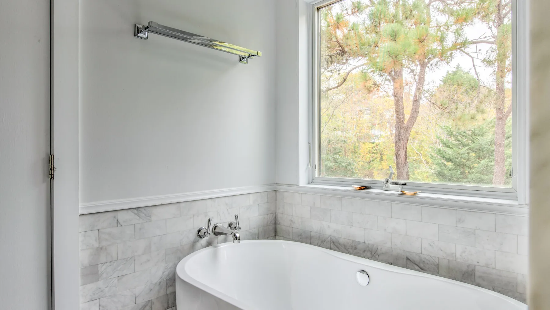 Un baño con una bañera bajo una ventana grande.