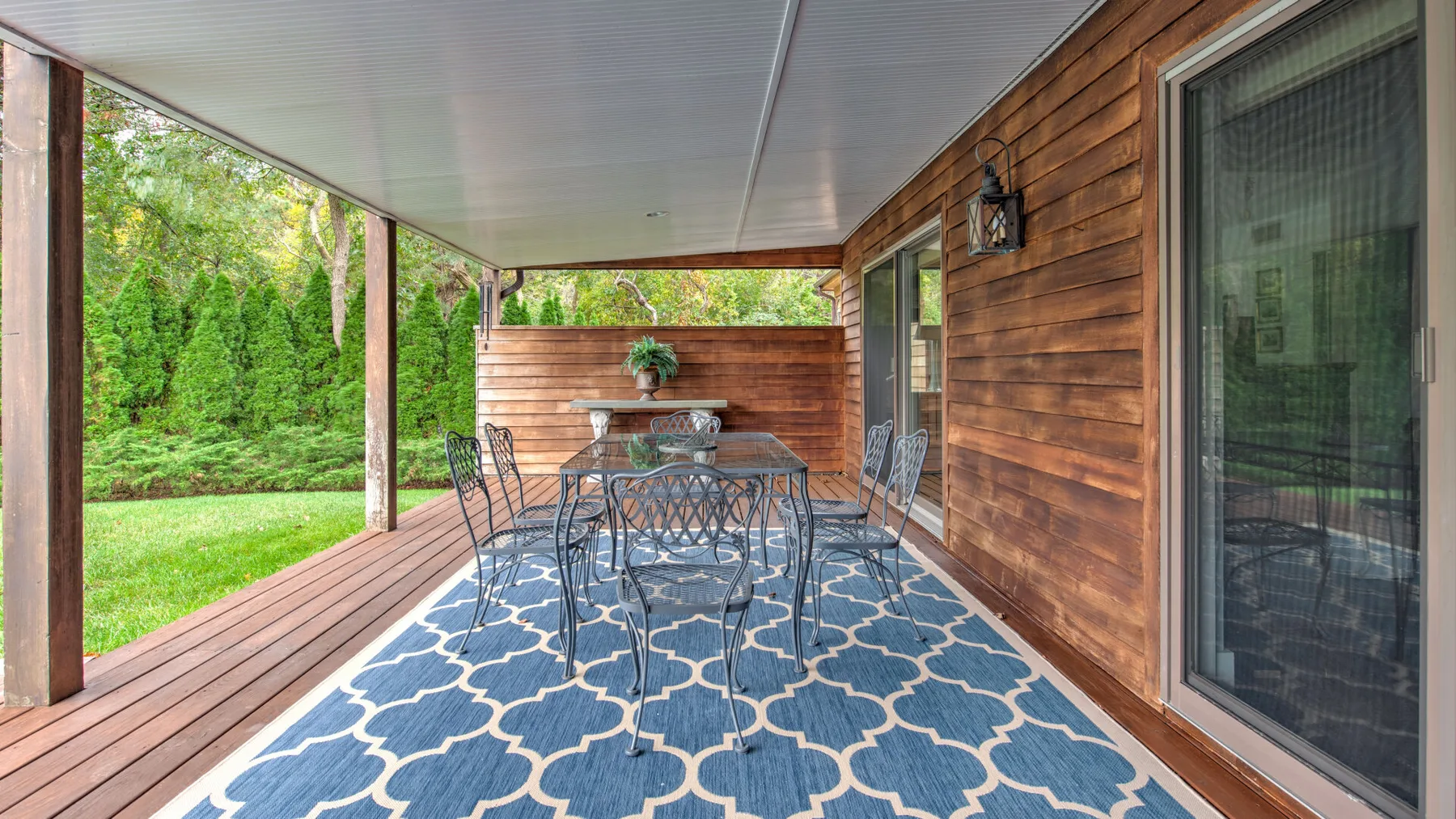 Una terraza cubierta de madera tiene una alfombra azul estampada y asientos al aire libre.