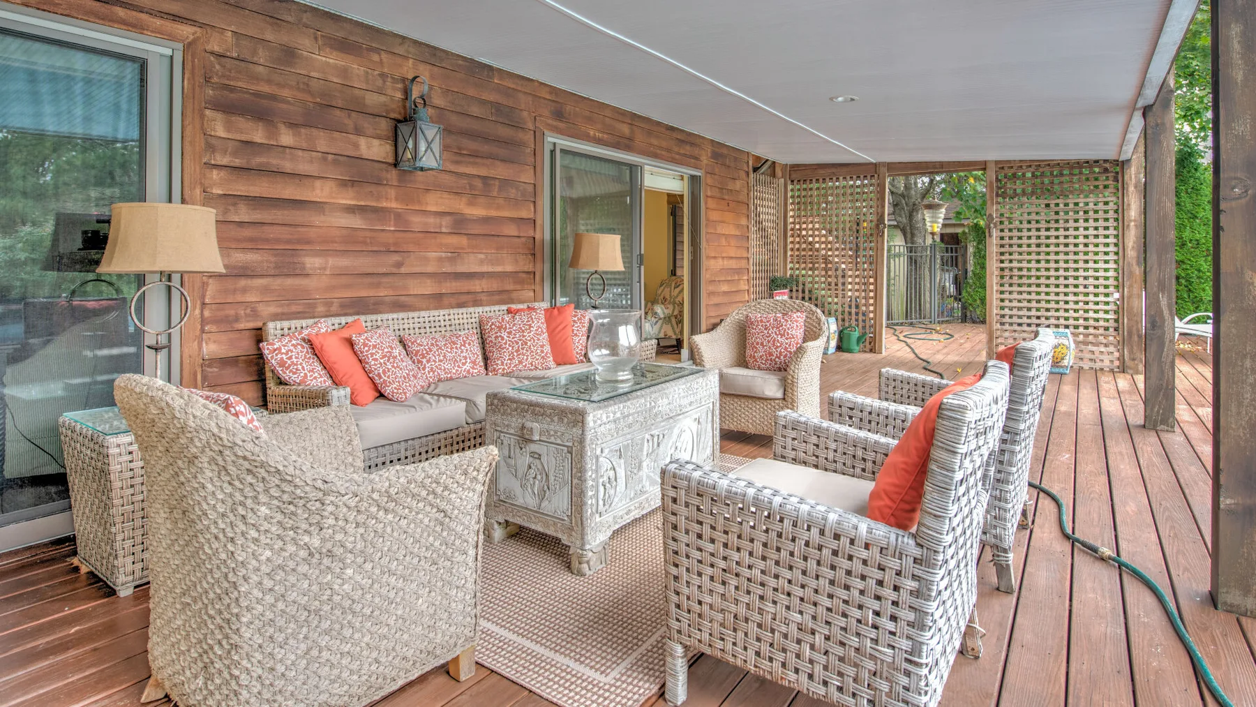 Una zona de estar exterior cubierta con muebles de mimbre y una mesa baja.