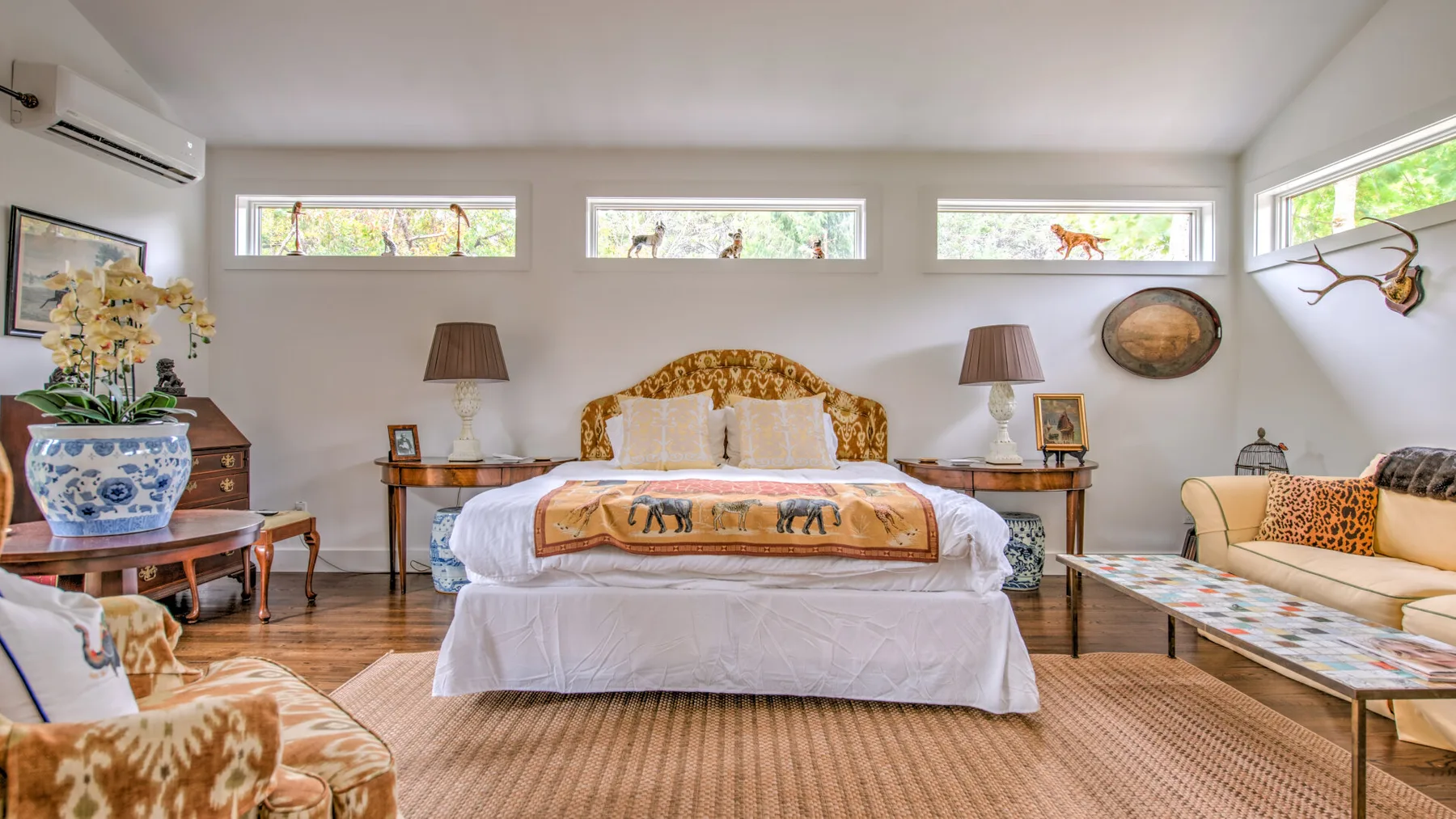 Un dormitorio con una cama entre mesas de noche y ventanas.