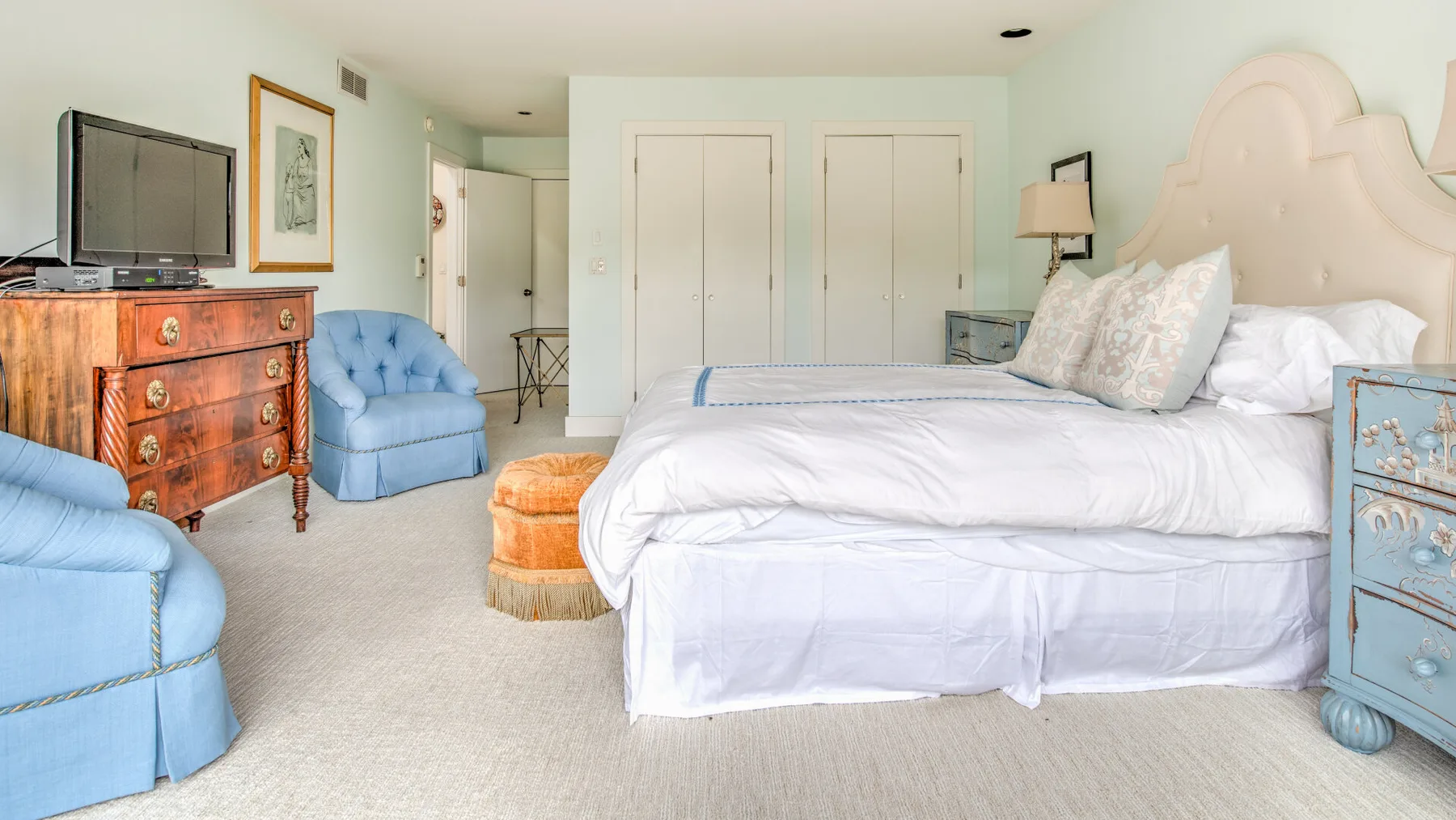 Un dormitorio luminoso con una cama grande y asientos azules.
