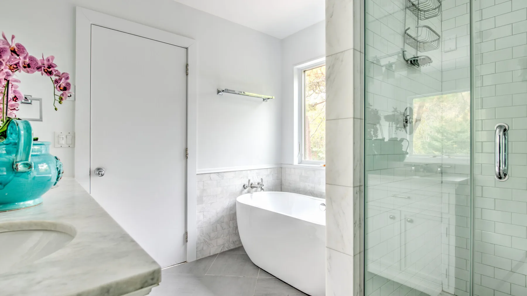Un baño luminoso con bañera independiente y ducha de vidrio.
