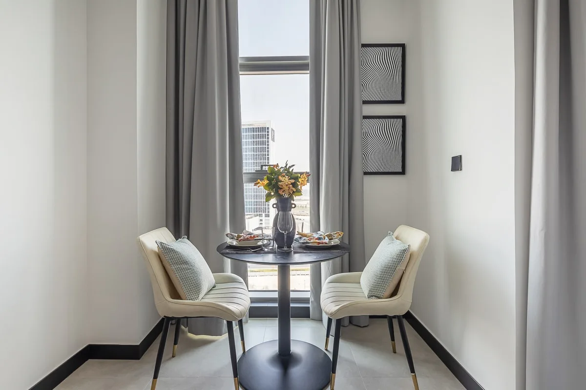 A small dining area with two seats beside a tall window.