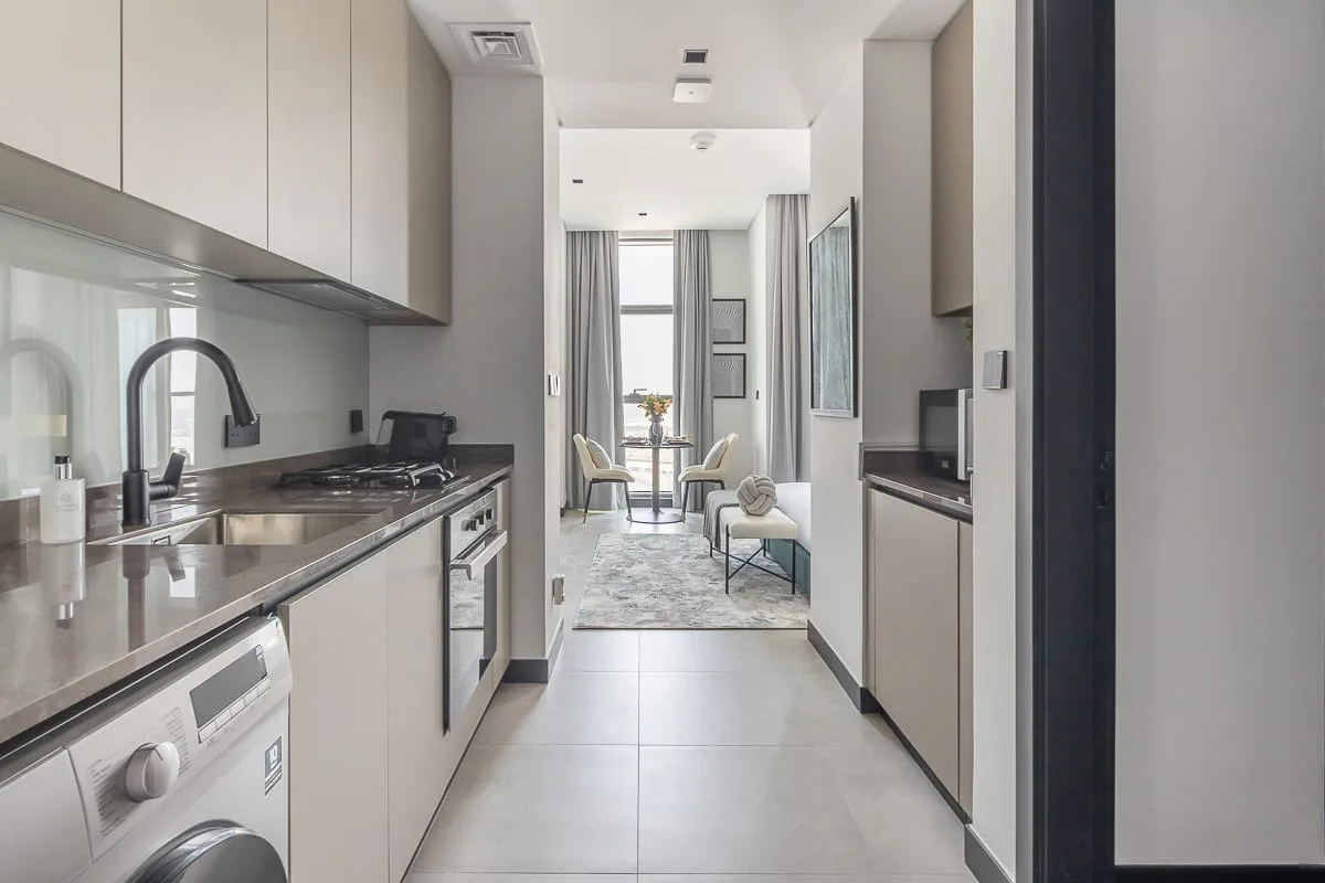 A modern galley kitchen opens into a bright dining and seating area.