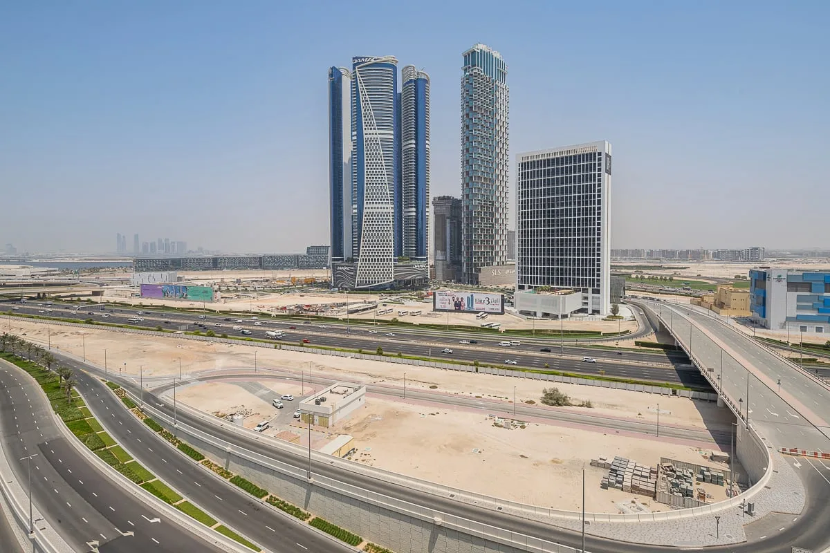 A cityscape of modern high-rise buildings beside a broad multilane road.