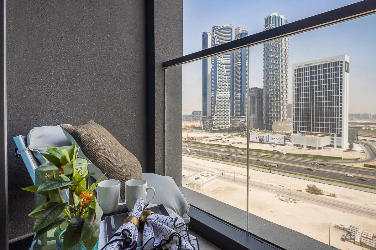 A balcony seating area overlooks a highway and several high-rise buildings.