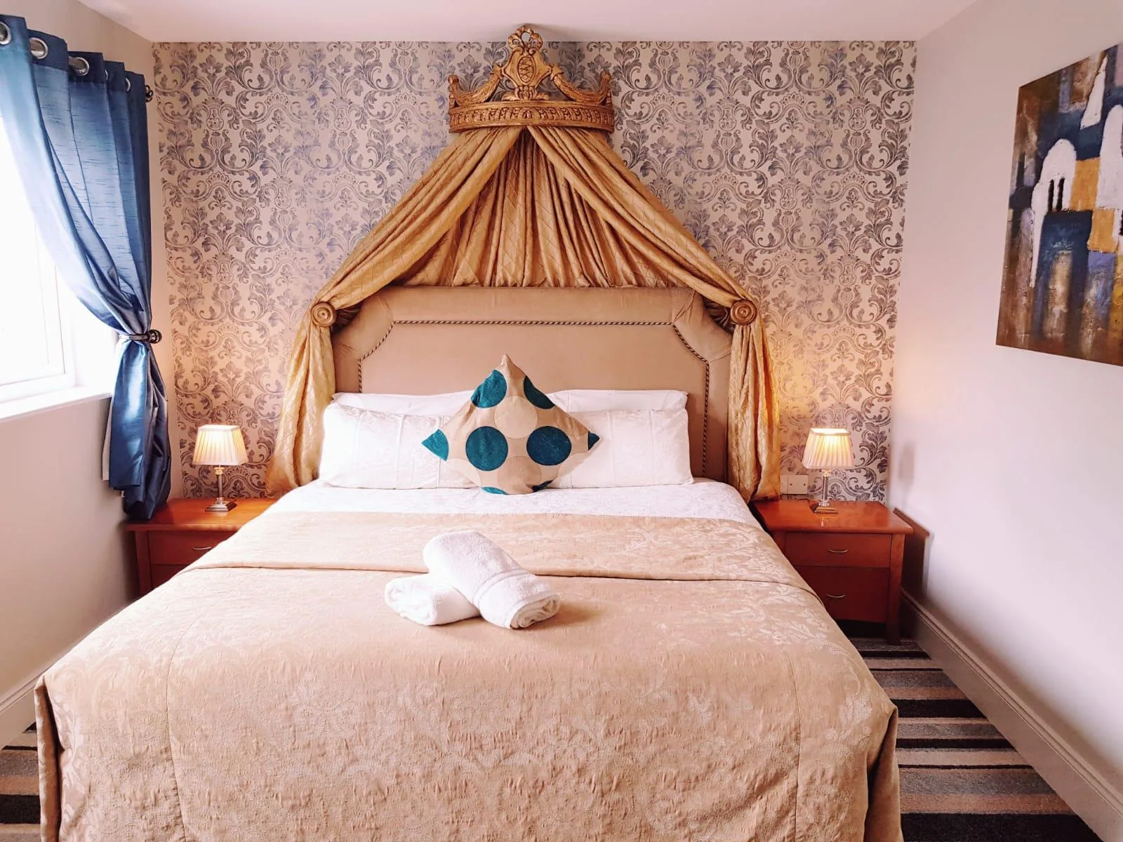 Habitación doble con ropa de cama dorada y cabecero de estilo dosel.