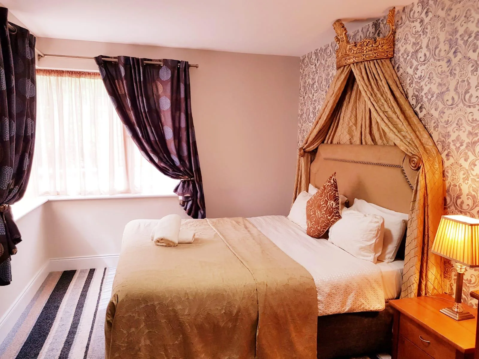 Habitación doble con cabecero de estilo corona y ropa de cama beige.