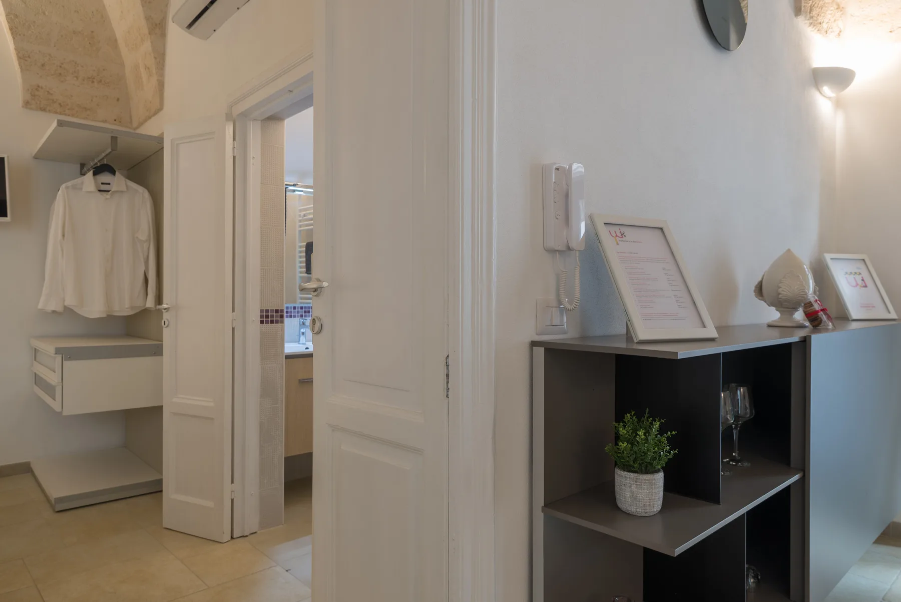 An interior hallway with an open doorway and a dark shelving unit.