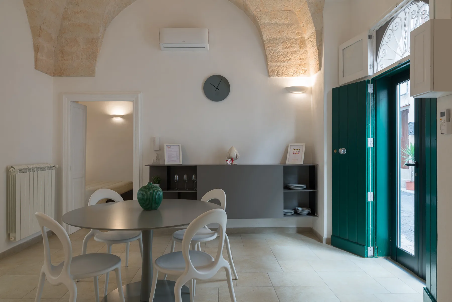 A dining area with a round table and chairs beneath a stone arch.