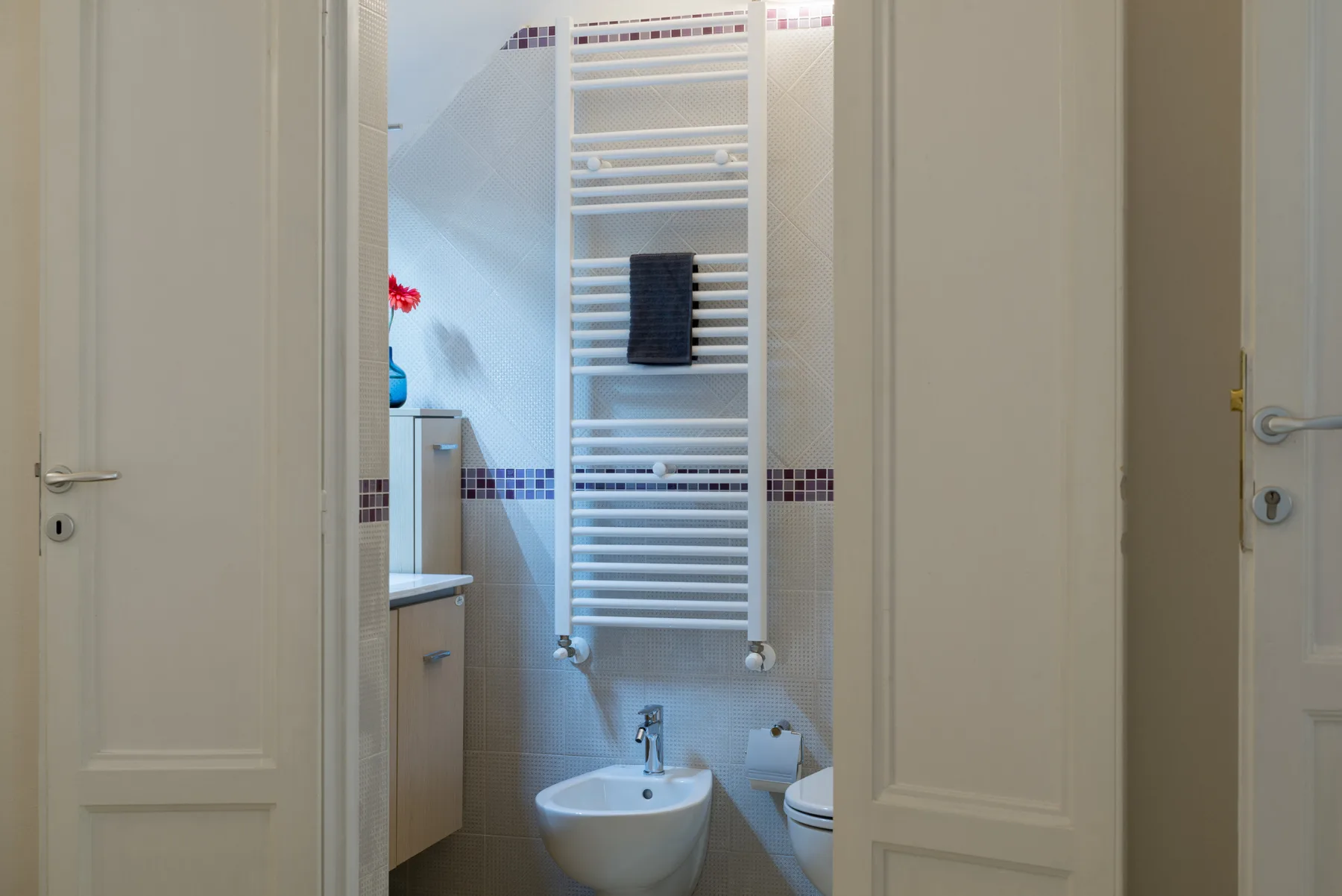 A bathroom with a wall-mounted towel warmer and a sink.