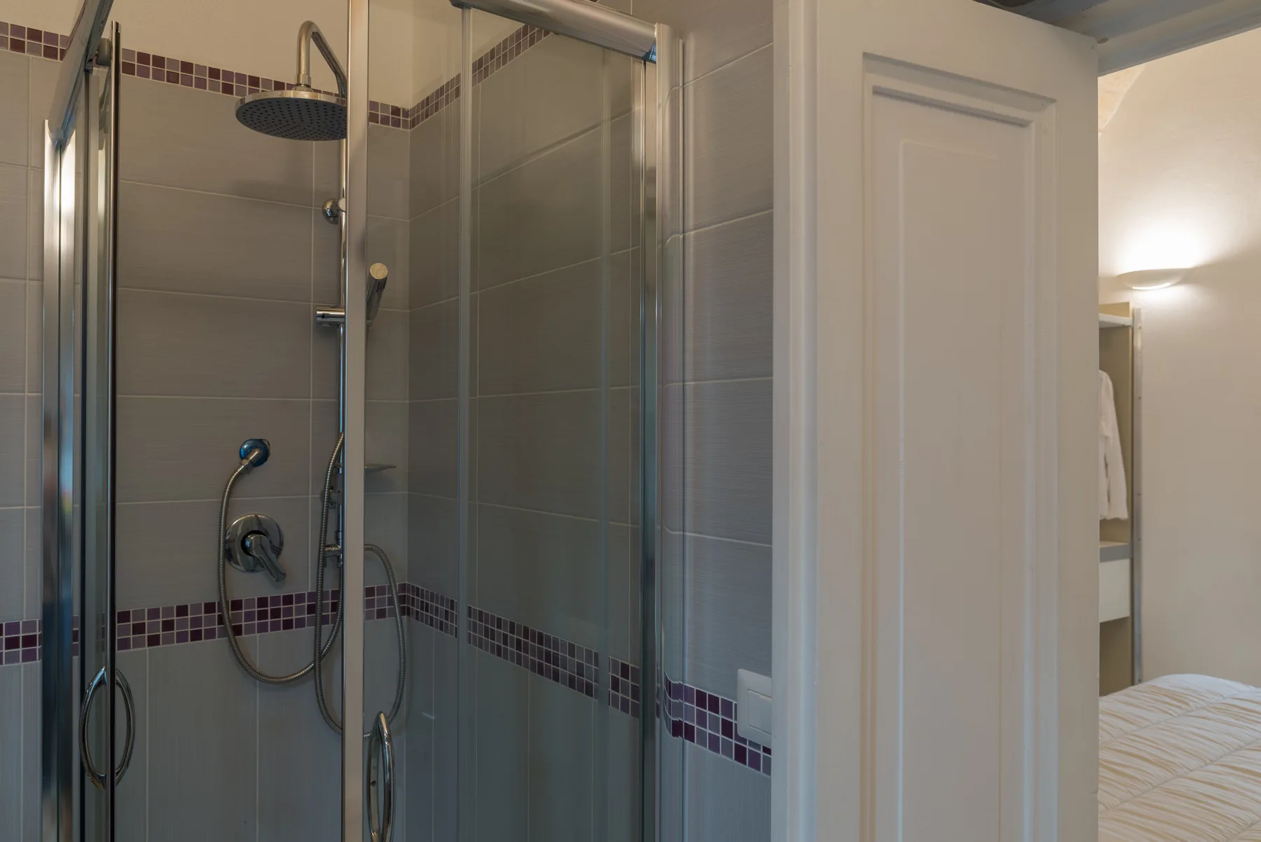 A tiled bathroom shower with glass panels and chrome fixtures.