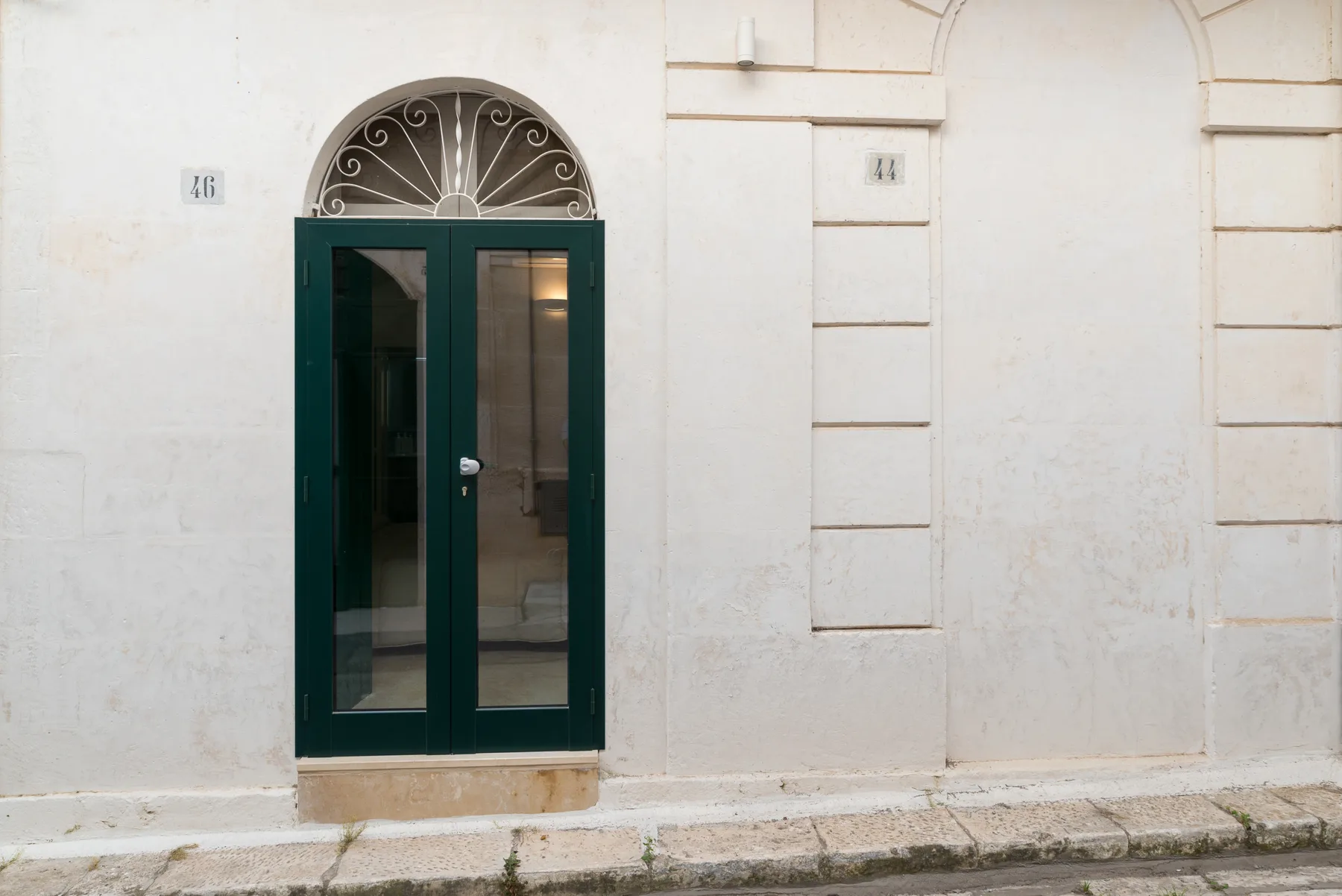 A dark green glass doorway set into a pale stone facade.
